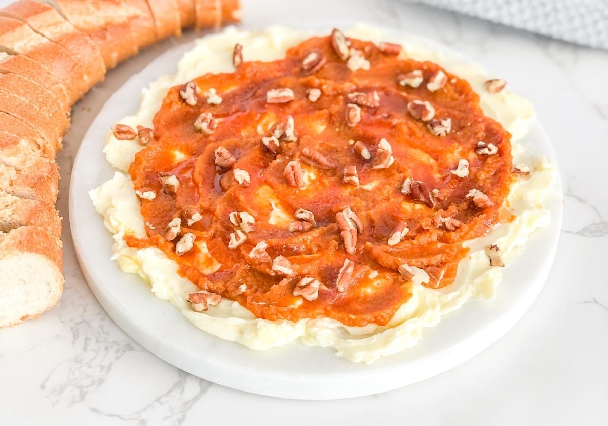 pumpkin butter board with honey and pecans on a marble platter