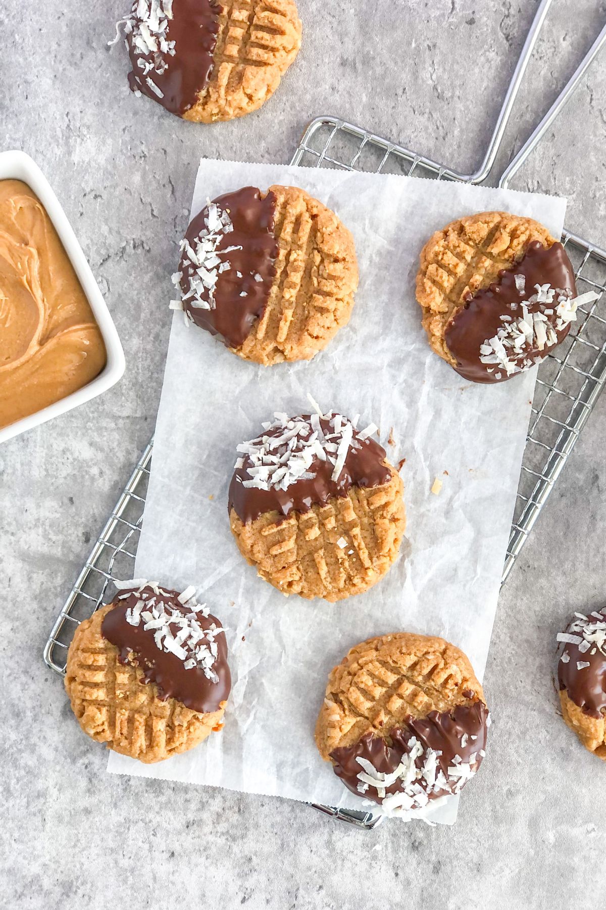 chocolate-dipped flourless peanut butter coconut cookies on parchment paper