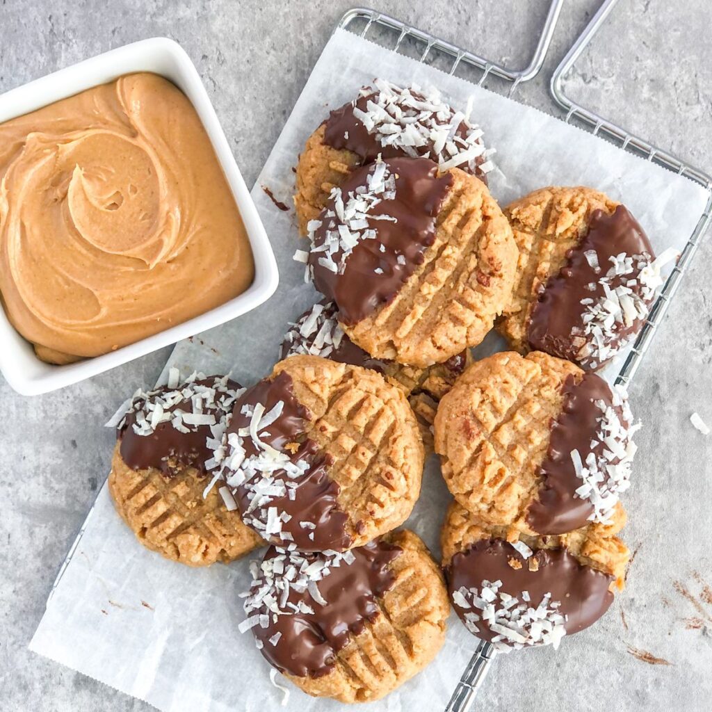 chocolate-dipped flourless peanut butter cookies with coconut on parchment paper