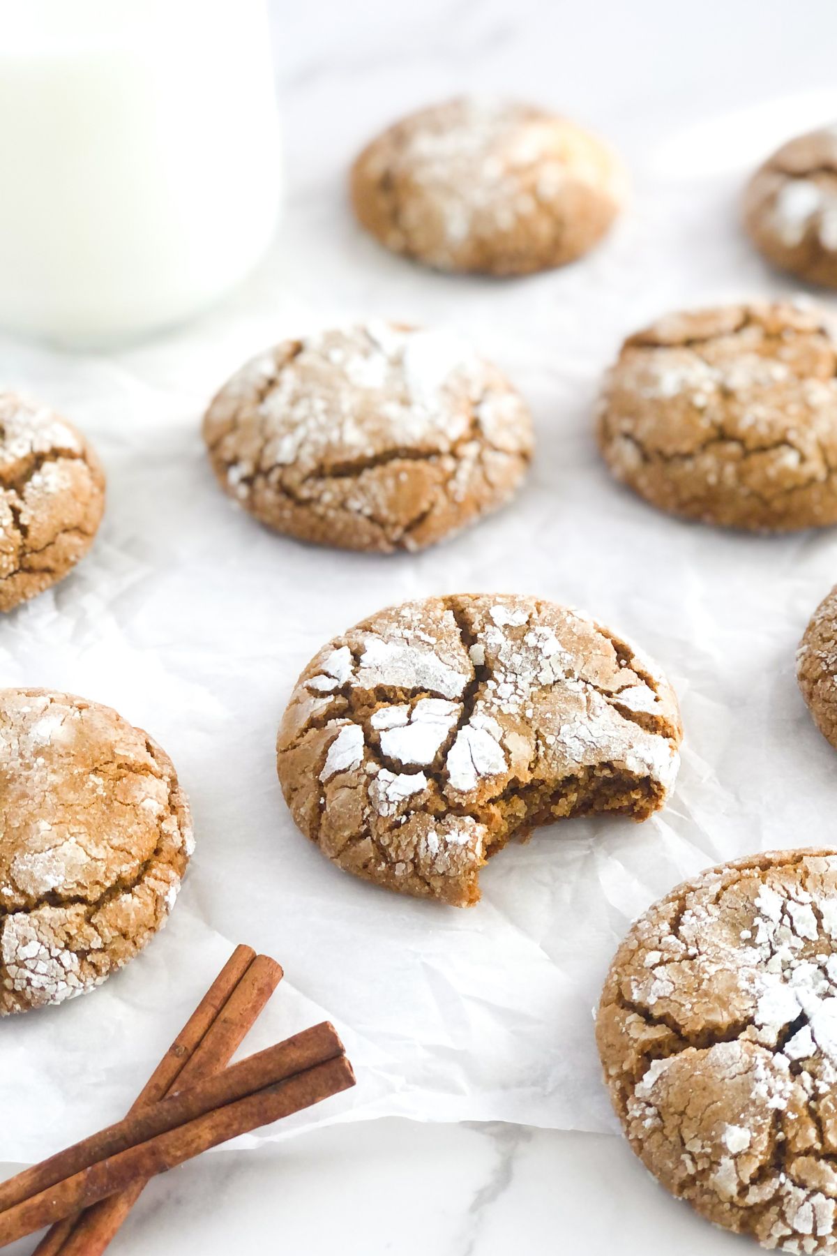 ginger molasses crinkle cookies on parchment paper with cinnamon sticks