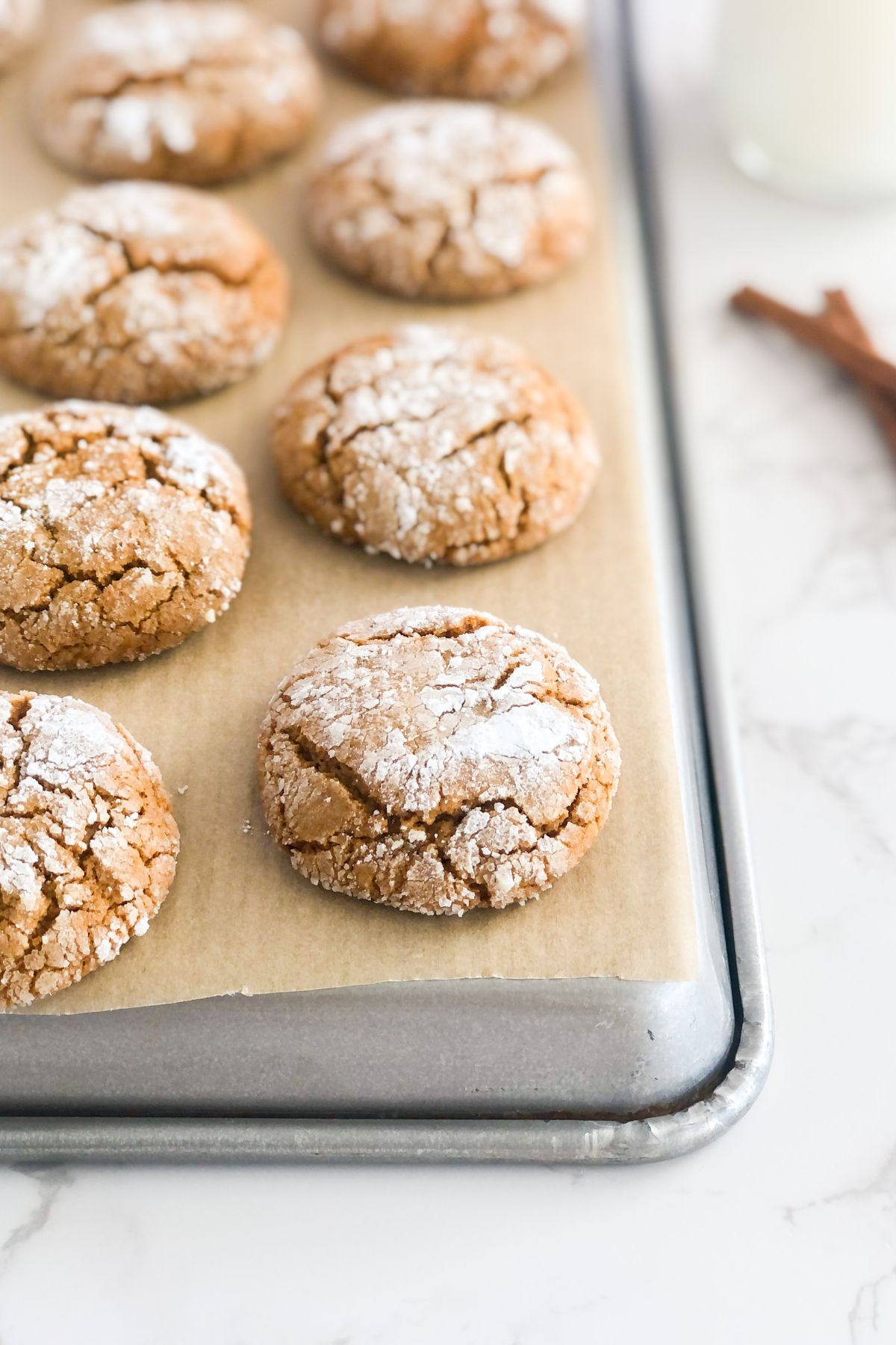 crinkle cookies with powdered sugar on a baking sheet with parchment paper