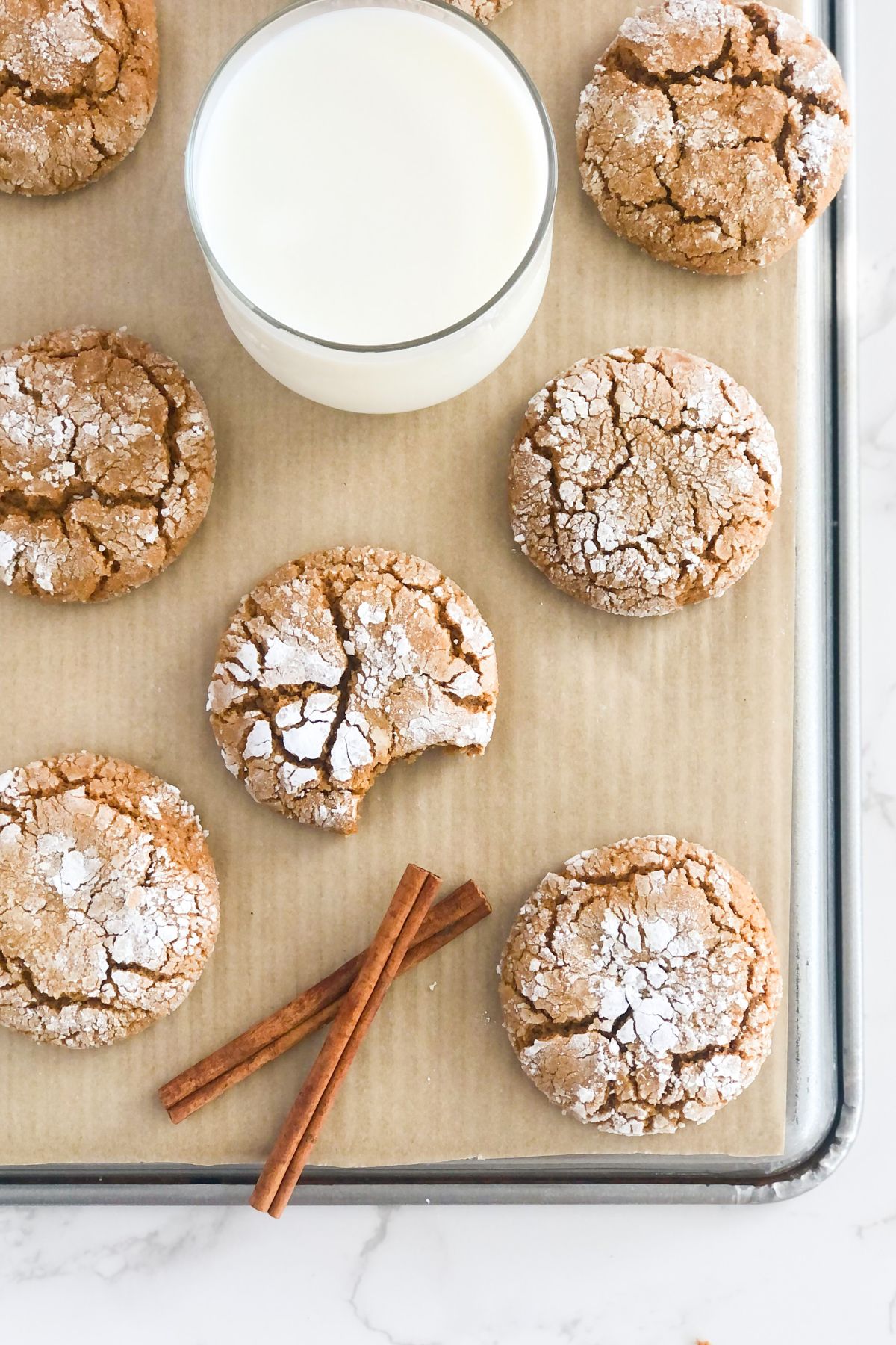 spiced molasses crinkle cookies with powdered sugar on a baking sheet