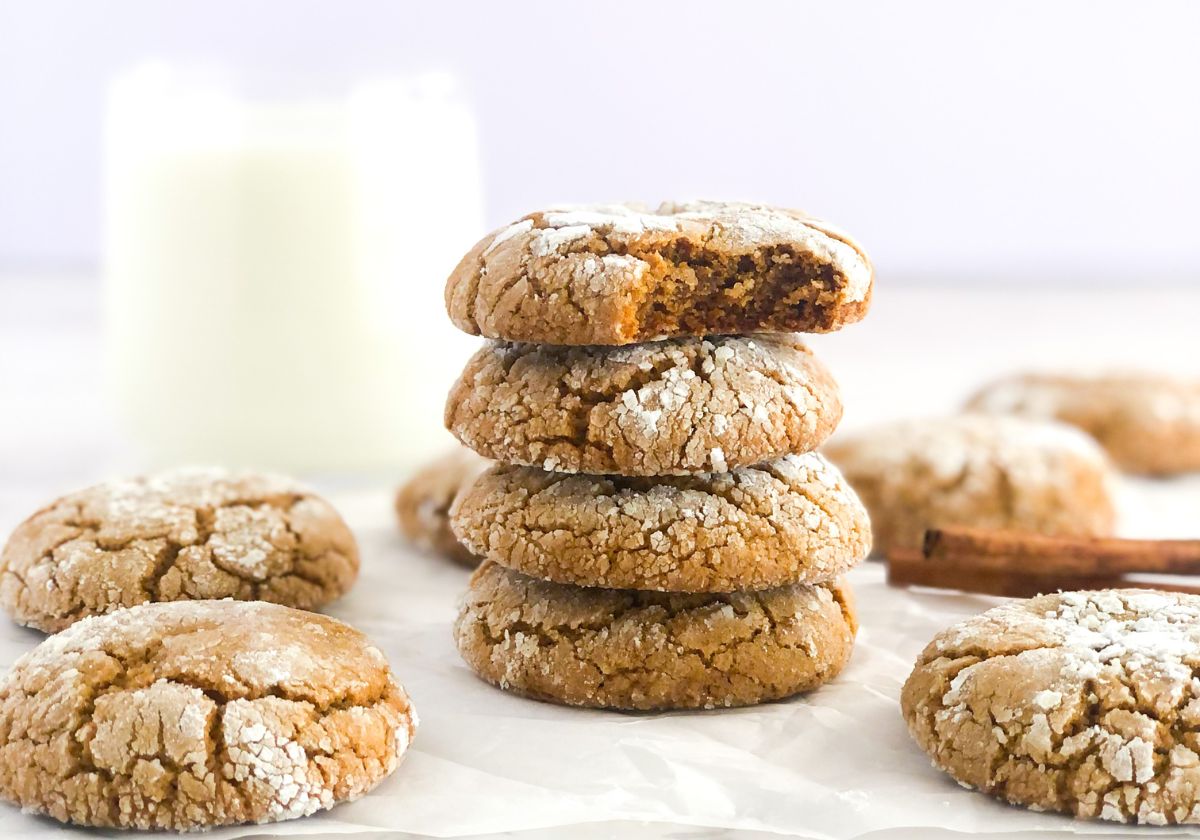 stack of ginger molasses crinkle cookies with a glass of milk