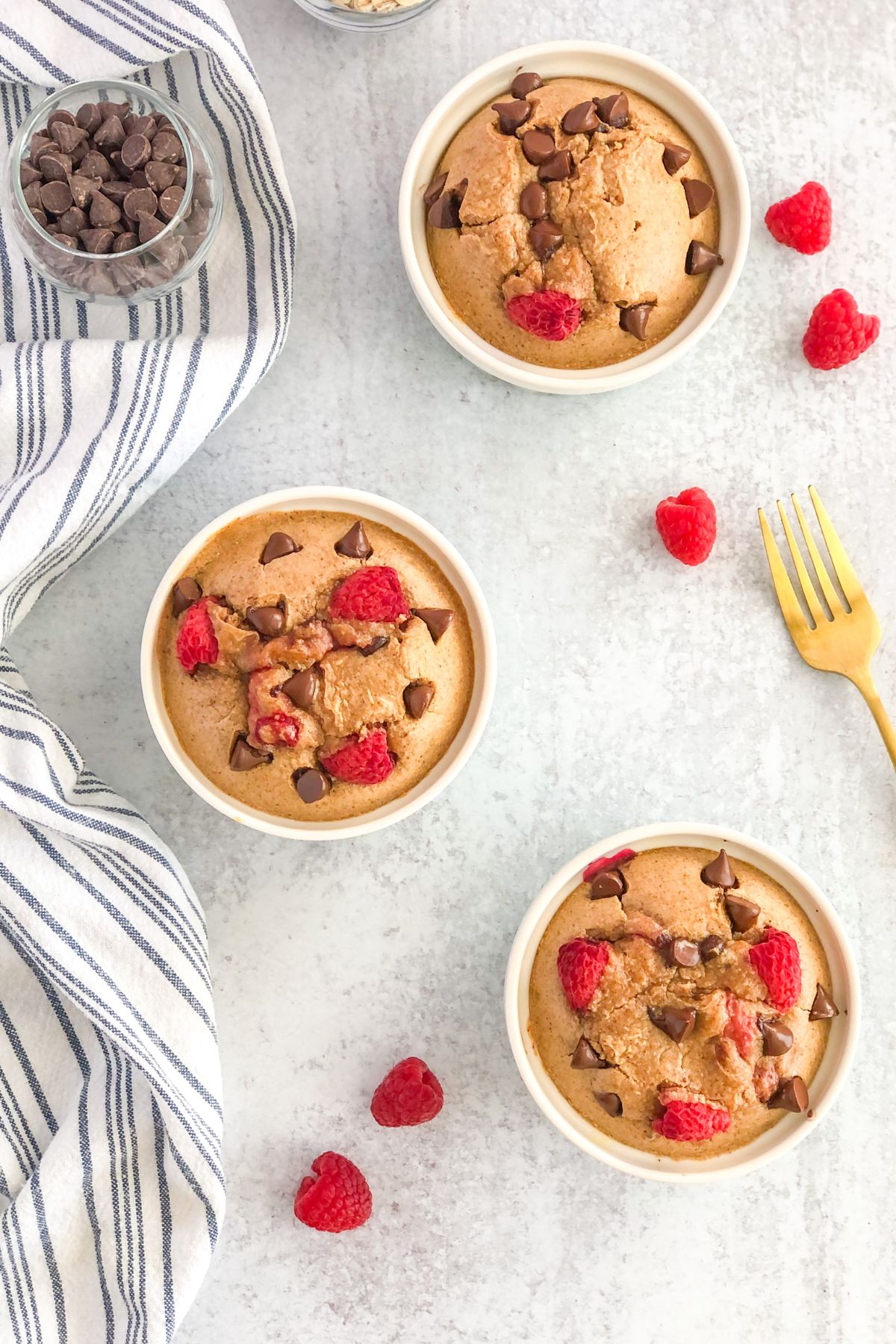 individual chocolate chip baked oats with raspberries in ramekins