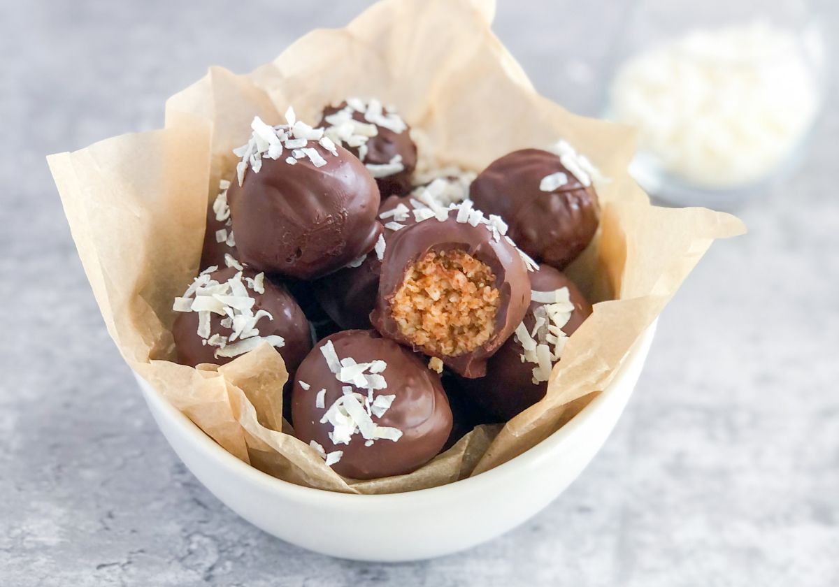 dark chocolate bites with coconut almond butter filling in a bowl with parchment paper