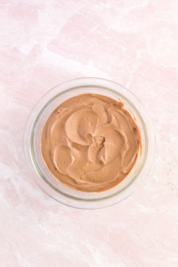 yogurt and cocoa powder with maple syrup in a glass mixing bowl