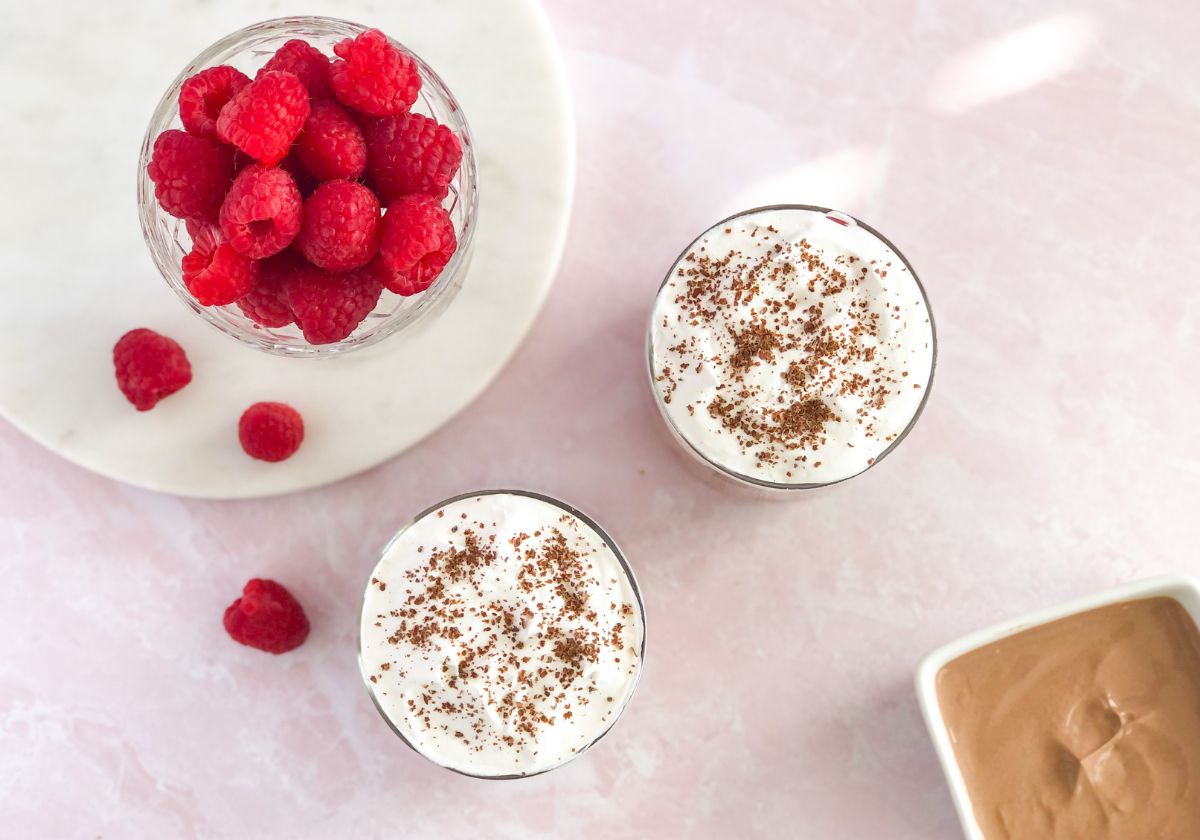 chocolate yogurt parfaits with raspberries and whipped cream in small jars