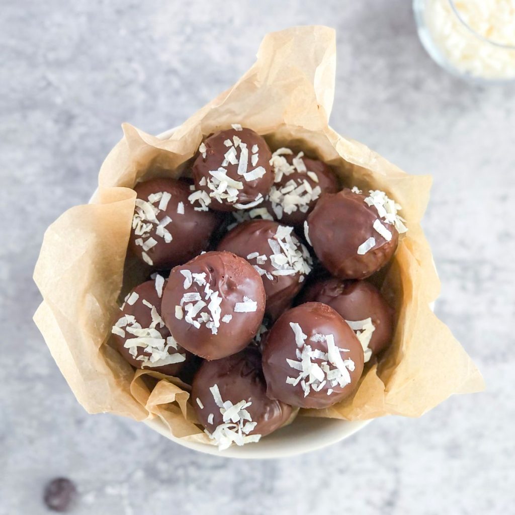 chocolate coconut truffles with almond butter in a small bowl with parchment paper