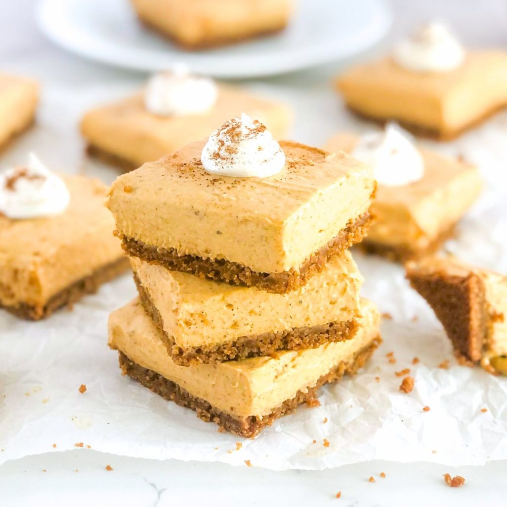 no bake pumpkin cheesecake bars stacked with whipped cream on top